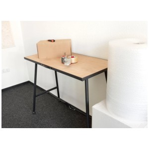 Établi pliant en bois FSC, noir, avec carton et matériaux d'emballage sur le plan de travail.