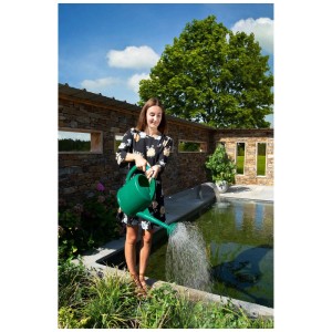 Femme arrosant des plantes avec un arrosoir en plastique vert de 7 l dans le jardin.