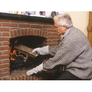 Uomo che usa guanti da lavoro LUX per mettere la legna nel camino. Il polsino lungo protegge dal calore.