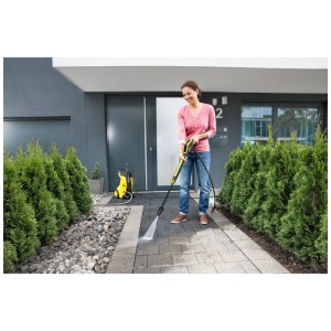 Femme nettoyant une allée avec le Kärcher Dirt Blaster DB 145 Full Control et un nettoyeur haute pression.