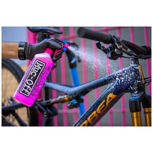 Muc-Off Reinigungsset: Fahrrad wird mit Reiniger aus pinkfarbener Sprühflasche eingesprüht.