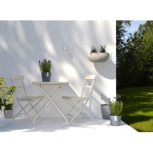 Pot de fleurs Ecopots Stockholm, gris-bleu, Ø 16cm, avec des plantes sur une table de jardin.