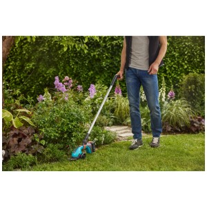 Cisailles à gazon sans fil Gardena PowerCut avec manche télescopique en utilisation dans le jardin.