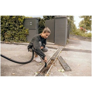 Donna pulisce una grondaia dalle foglie con l'aspiratore multiuso Kärcher WD 4 S V-20/6/22.