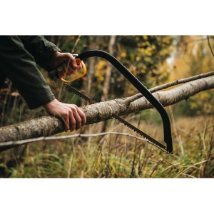 Scie à archet Fiskars SW30 en action : une personne scie une branche dans le jardin.