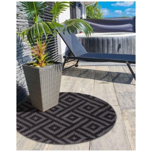 Runder Beliani Outdoor-Teppich Ajmer Schwarz Ø 120 cm mit geometrischem Muster aus Polypropylen auf Terrasse.