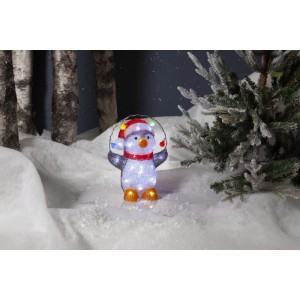 Pinguino LED Crystalo illuminato con cappello e sciarpa rossi, tiene luci colorate, in paesaggio invernale innevato.