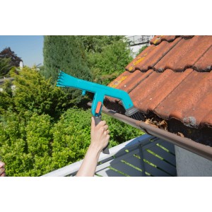Nettoyeur de gouttières Gardena combisystem en utilisation : Nettoyage des gouttières avec brosse et grattoir.