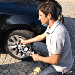 Homme vérifiant la pression des pneus avec le compresseur Einhell TC-AC 190. Compresseur pour voiture et vélo.