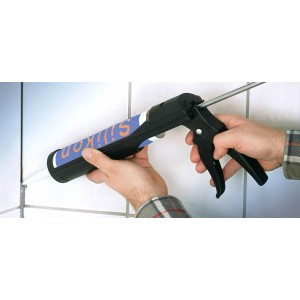 Pistolet à cartouche LUX Comfort appliquant du silicone sur des carreaux.