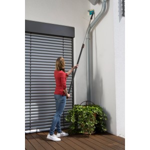 Donna che utilizza scopa angolare Gardena combisystem con manico per pulire una grondaia.