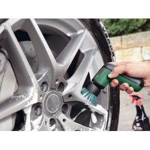 La spazzola a batteria Bosch Universal Brush pulisce un cerchione d'auto argentato con schiuma.