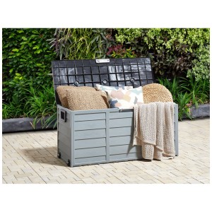 Coffre de rangement Beliani Locarno gris ouvert avec coussins et couverture dans le jardin.