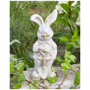 Weisse Beliani Gartenfigur Hase Simard mit Schaufel, verwitterte Optik, kupferfarbene Details, im Grünen.