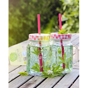 Deux verres de boisson au aspérule odorante avec paille et pot d'aspérule odorante en arrière-plan.