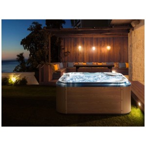 Spa extérieur Beliani Tularosa aspect bois, éclairage LED bleu et eau bouillonnante dans un jardin de nuit.