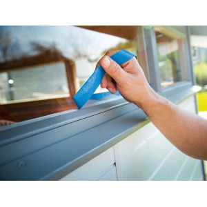 Anwendung von blauem LUX Flachkrepp Exact Line Outdoor Klebeband auf einem Fensterrahmen.