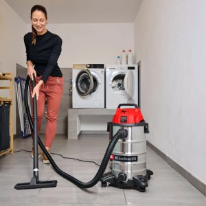 Frau nutzt Einhell Nass-Trockensauger TC-VC 3055 S mit 30 l Edelstahlbehälter zur Bodenreinigung in einer Waschküche.
