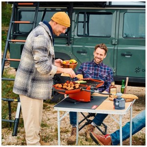 Nomadiq Gasgrill Modell 3.0 Terra-Rot beim Grillen im Freien.