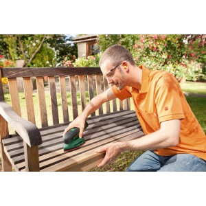 Homme ponçant un banc en bois avec la ponceuse multifonction sans fil Bosch EasySander 12. Ponceuse compacte pour petites surfaces.