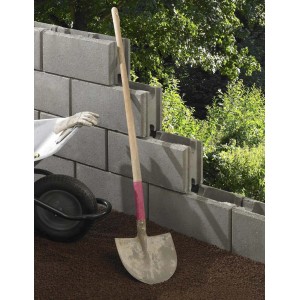 Blocs de coffrage gris 17,5 cm comme mur de jardin avec brouette et pelle.