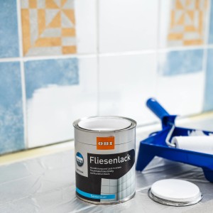 OBI Fliesenlack Weiß seidenmatt (750ml) mit Farbrolle vor Fliesenwand.