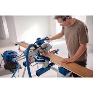 Uomo taglia legno con sega troncatrice Bosch Professional GCM 305-216 D. Aspirazione polvere e prolunga tavolo.