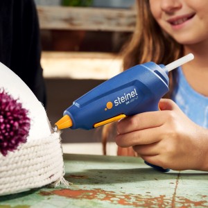 Pistolet à colle chaude Steinel GlueMatic 1007-LT en utilisation, idéal pour le bricolage avec des matériaux thermosensibles.