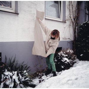 Femme appliquant une housse pour rosiers (lot de 3) pour protéger les rosiers de la neige. Film et polaire.
