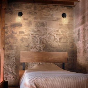Spot noir Briloner 1-Spot Pearl E27 sur mur en pierre au-dessus du lit, look rétro.
