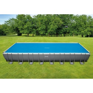 Piscine rectangulaire Intex Ultra Frame avec couverture solaire bleue 975x488 cm dans le jardin.