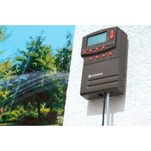 Programmation d'arrosage Gardena avec câble de connexion et arroseur de pelouse en utilisation.
