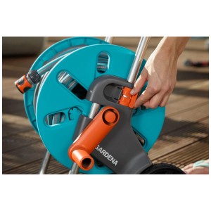 Set carrello avvolgitubo Gardena AquaRoll S con tubo e lancia, mano che aziona il meccanismo di blocco.