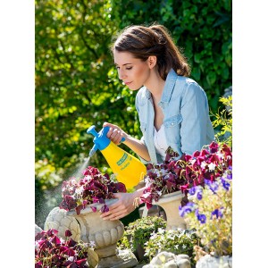 Femme utilisant un pulvérisateur à pression Gloria Hobby 100 jaune pour l'entretien des plantes.
