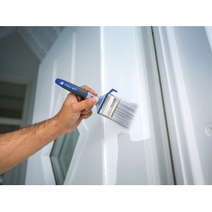 Mano che dipinge una porta bianca con pennello piatto LUX per vernice 60mm. Pennello con gancio per secchio.