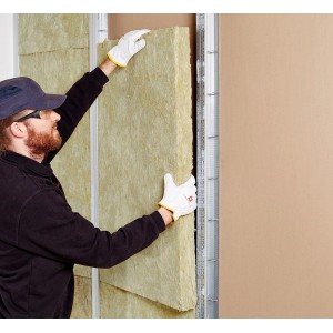 Homme installant un panneau de séparation Rockwool Sonorock (100 mm) dans une cloison à ossature métallique.