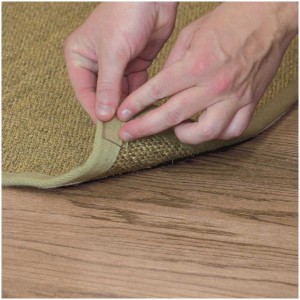 Application du ruban adhésif double face transparent Monster Tape pour fixer un tapis sur un plancher en bois.