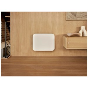 Termoconvettore Mill Invisible Smart WiFi bianco, 400 W, su parete in legno chiaro. Ideale per bagni moderni.
