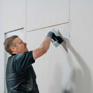 Artigiano che applica lo stucco fine Knauf Uniflott Finish su una parete in cartongesso.