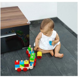 Reer Eckenschutz transparent, 4 Stück, an einem Tisch befestigt, mit spielendem Baby im Vordergrund.