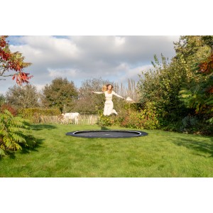 Trampolino interrato nero Exit InTerra Ø 244 cm con persona che salta in giardino.