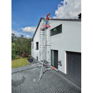 Impalcatura in alluminio Krause Monto ClimTec con seconda estensione di fronte al muro di casa. Persona sulla piattaforma superiore.