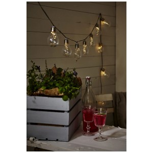 Guirlande solaire Star Trading Glow (180 cm) avec des boules transparentes dans le jardin.