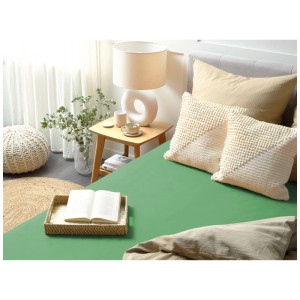 Lenzuolo con angoli in cotone verde 180x200 cm su letto, con cuscini e comodino.