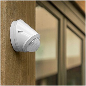 Rilevatore di movimento Steffen bianco IP65 con rilevamento a 360° su parete di legno.