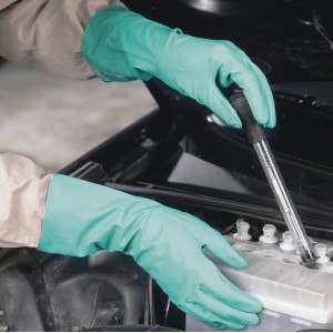 Mani con guanti protettivi in nitrile LUX taglia 8 controllano la batteria dell'auto.