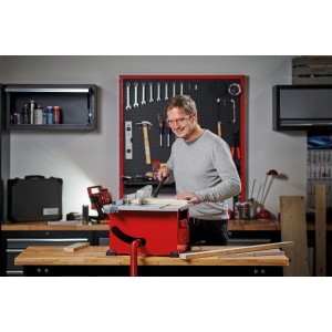 Einhell Scie circulaire sur table TC-TS 210 en utilisation : homme coupant du bois avec la scie rouge dans l'atelier.