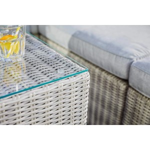 Gros plan : Fauteuil lounge Olea en résine tressée couleur sable avec plateau en verre et boisson. Mobilier de jardin pour des heures de détente.