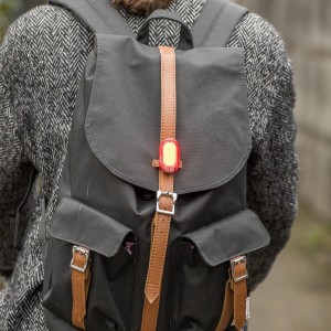 Feu arrière Infini Olley, noir, avec batterie, fixé sur un sac à dos.