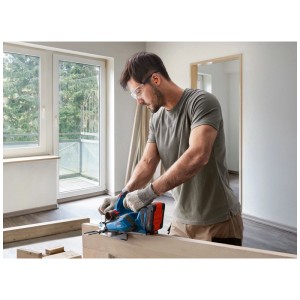 Uomo che pialla legno con pialla a batteria blu Bosch Professional GHO 18V-26. Pialla per lavorazione precisa del legno.